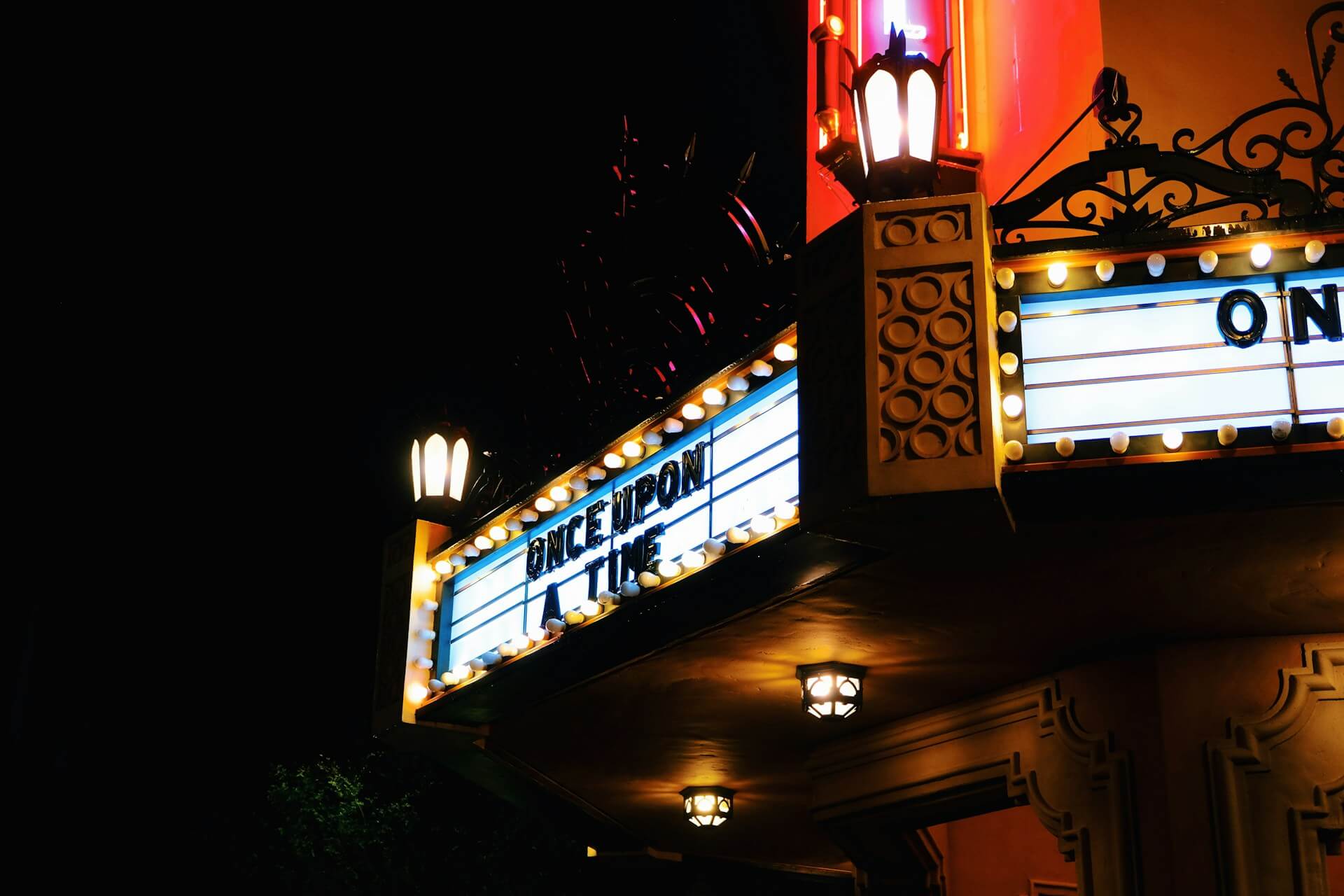 Illuminated theater marquee displaying 'Once Upon a Time' with vintage light bulbs and ornate lamp posts at night
